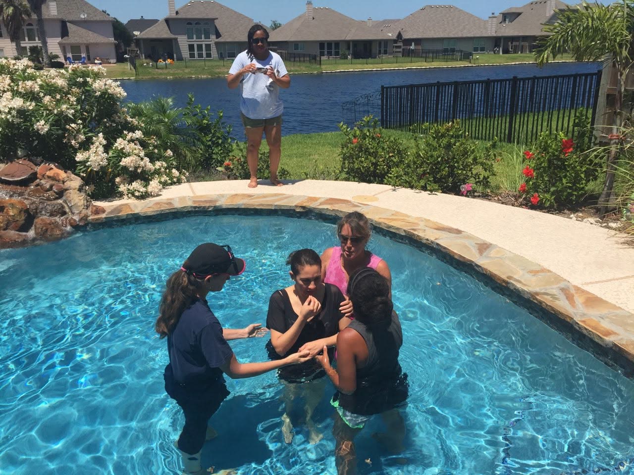 A baptism taking place in a backyard swimming pool