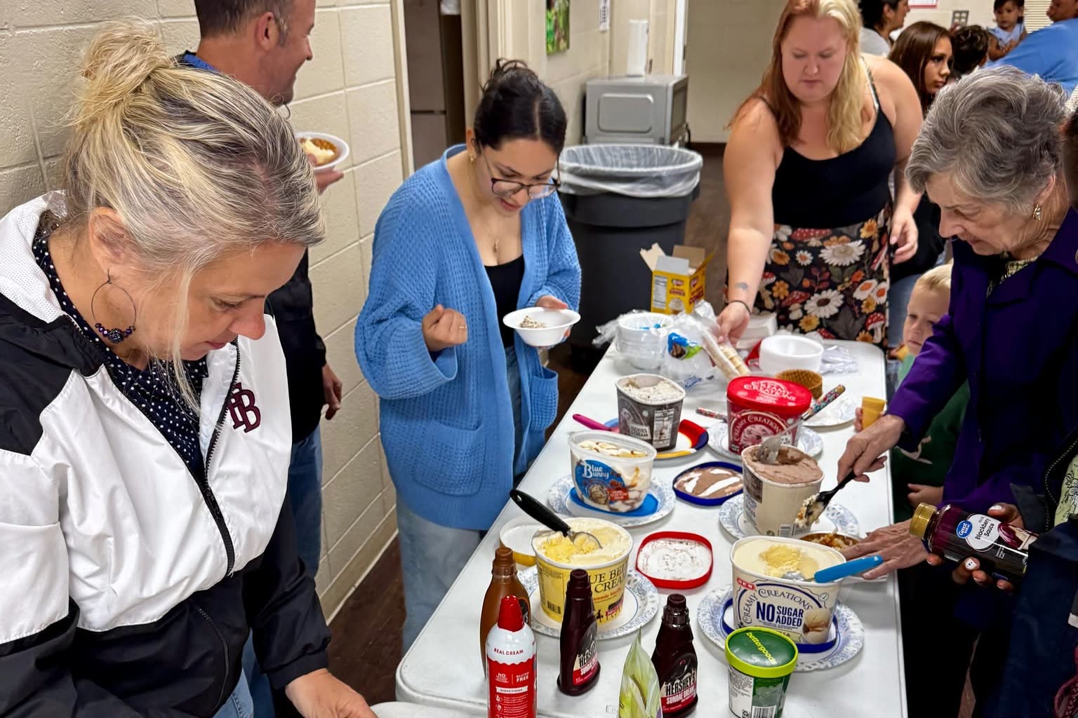 Church members building ice cream sundaes at a long fellowship table