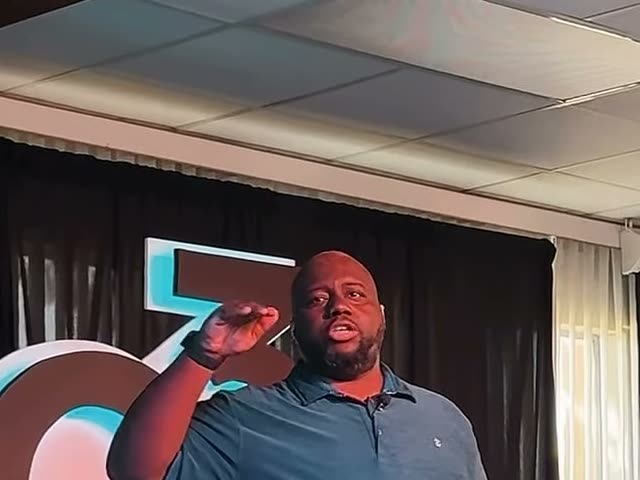 A man speaking on stage beside the GC3 logo