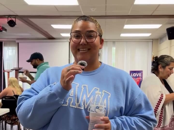 A smiling woman in a casual light blue sweatshirt